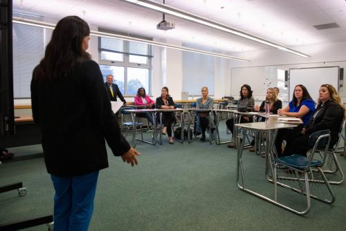 Mrs. Ashley Smith briefs U.S. Armed Forces senior leaders' spouses at Aviano Middle/High School during a base tour at Aviano Air Base, Italy, Oct. 13, 2022. The senior leaders' spouses learned about what makes Aviano schools unique within Department of Defense Education Activity DoDEA and the goals they have for the near future.